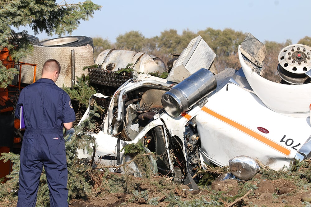 Man standing in front of an overturned semitruck